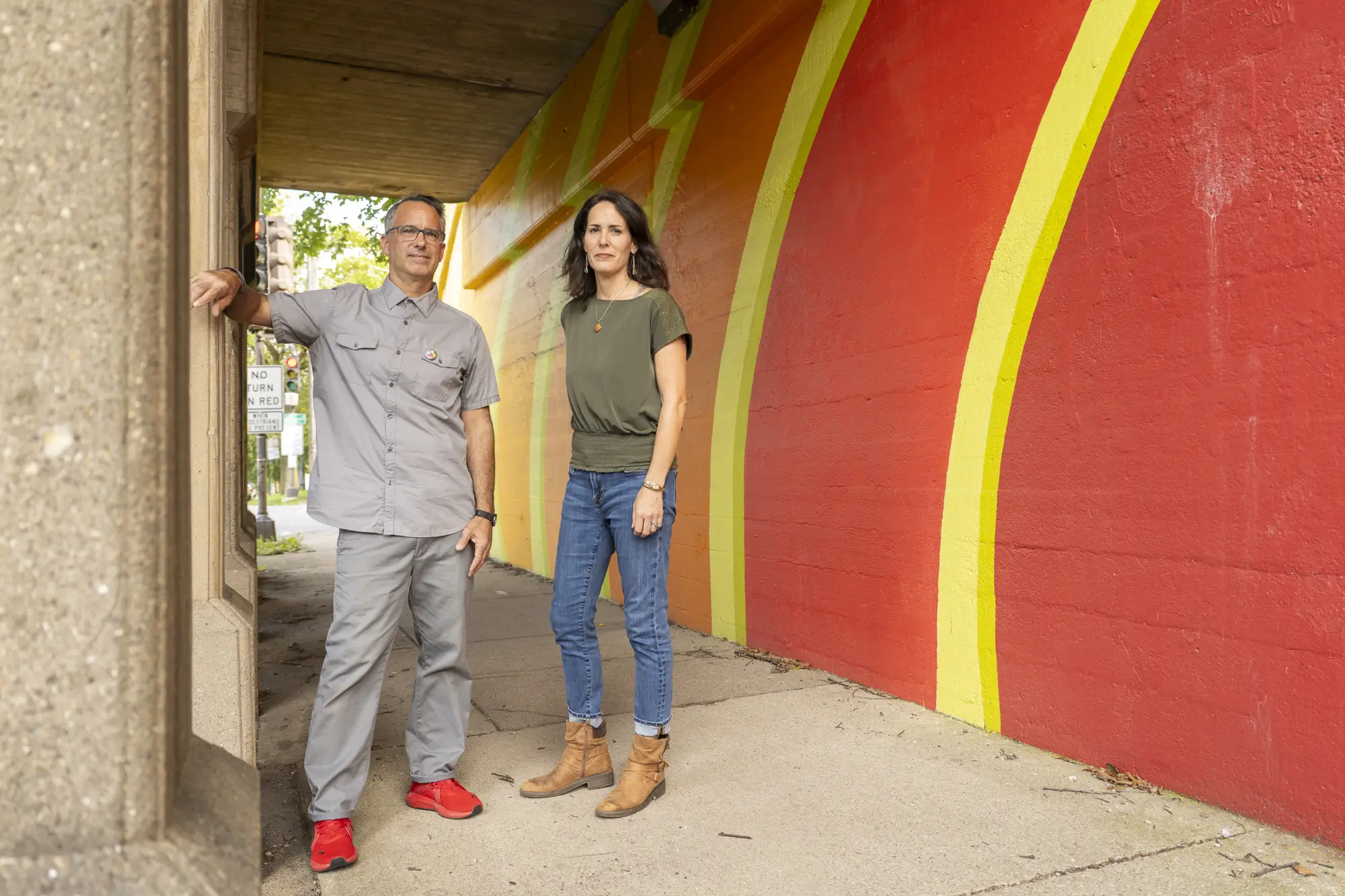 Man and woman stand next to public art mural